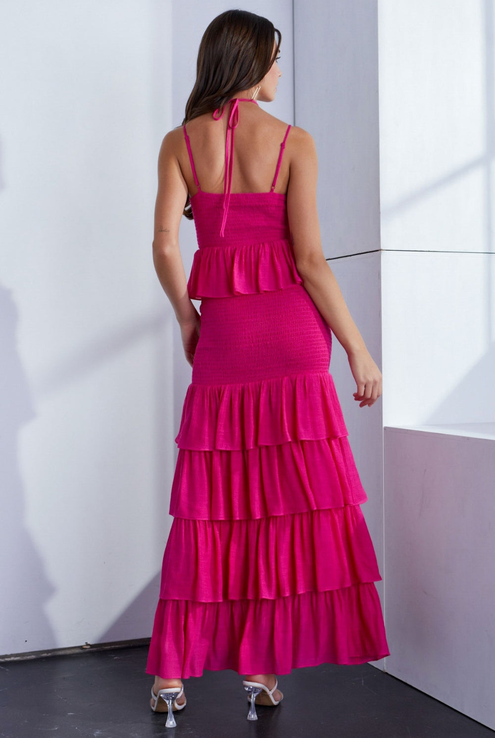 A woman wearing a vibrant pink ruffled dress with layered detailing and a sleeveless design, exuding elegance and playful femininity.