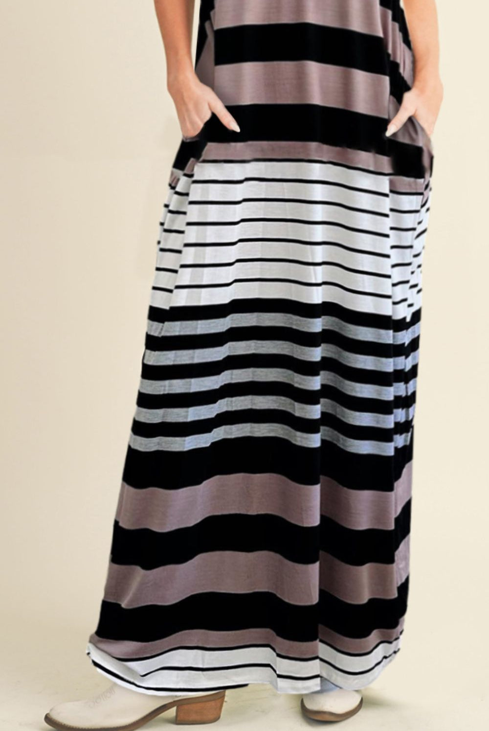 Model elegantly wearing a striped black and white maxi camisole dress