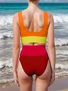 Woman joyfully wearing a two-piece bikini with a vibrant orange and yellow top and red high-waisted bottoms