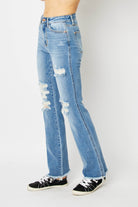 Model wearing light wash women's ripped bootcut jeans with distressed details