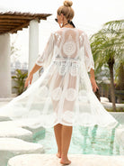 Fashionable woman in a white lace cover up with half sleeves and open front, ideal for beach outings.