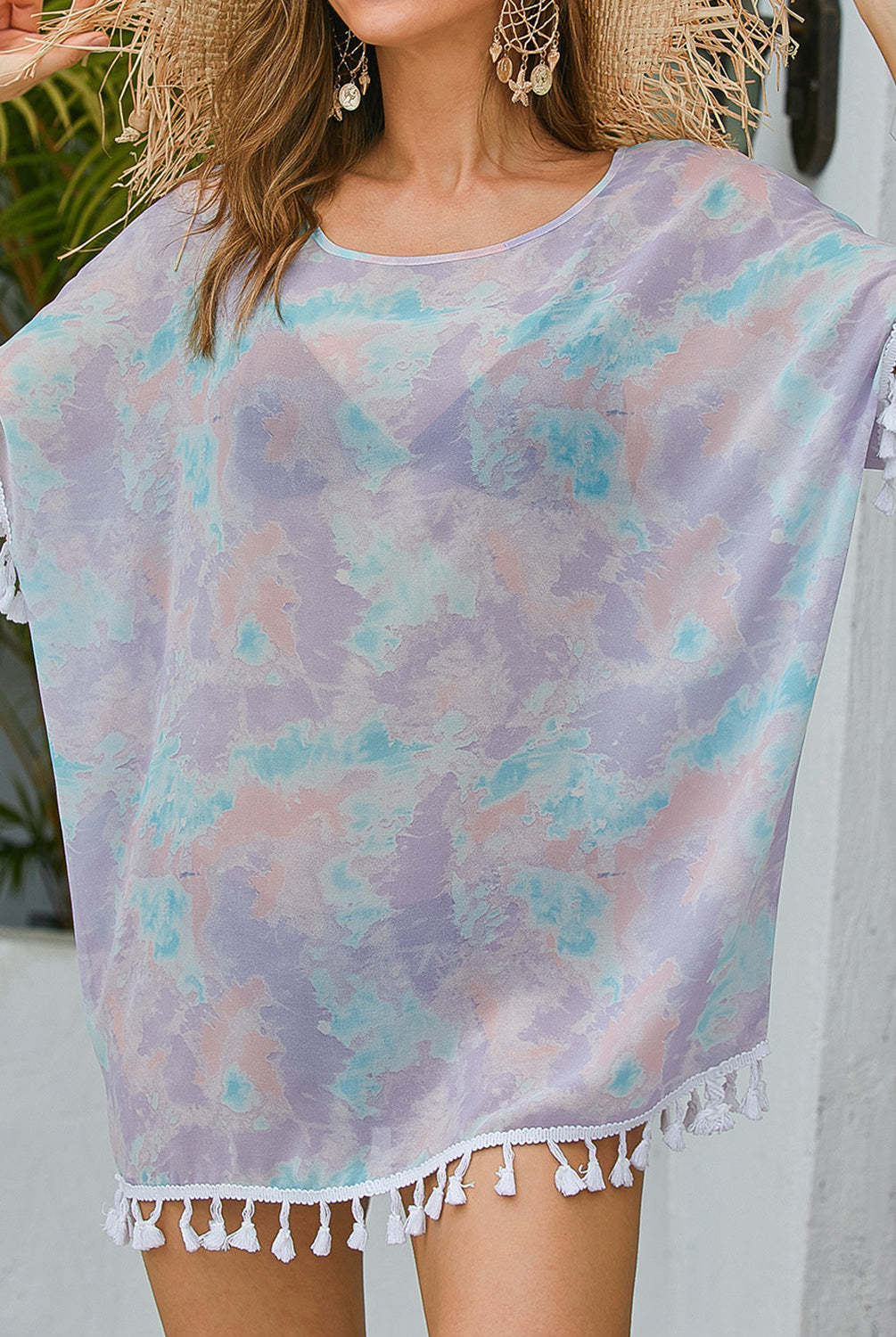 Woman in a colorful watercolor print cover up with tassel details, ideal for a stylish beach look.