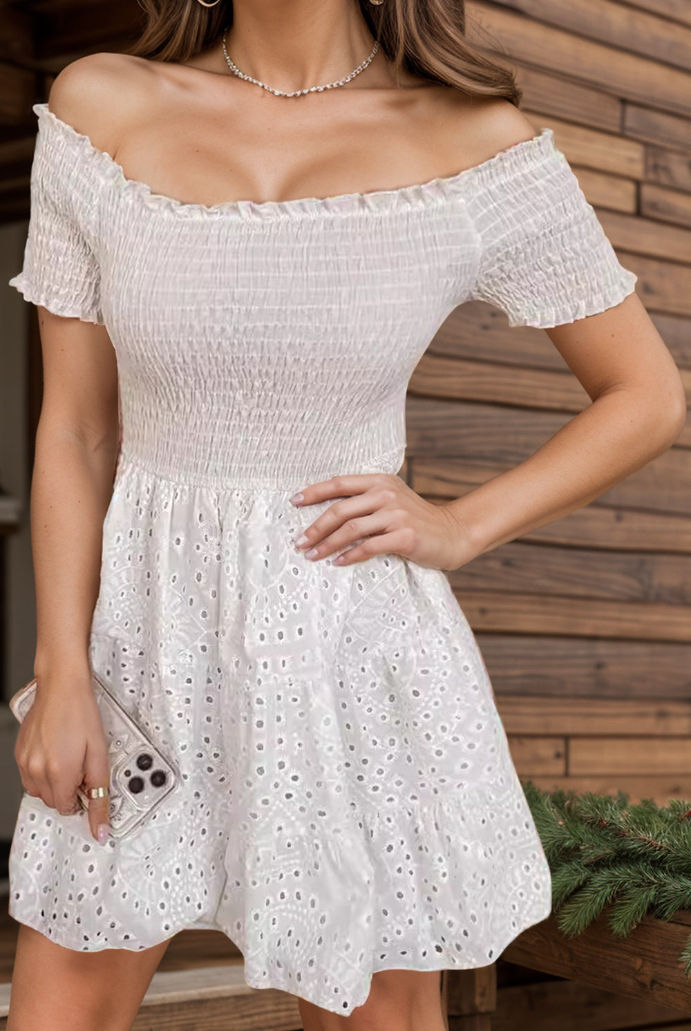 A woman radiates casual elegance in a white smocked mini dress with off-shoulder sleeves, perfect for spring and summer occasions.