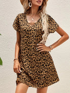 A fashionable woman exudes confidence in a leopard print mini dress, featuring a relaxed fit and a flirty length, paired with statement jewelry and a poised attitude, perfect for a casual yet stylish outing.