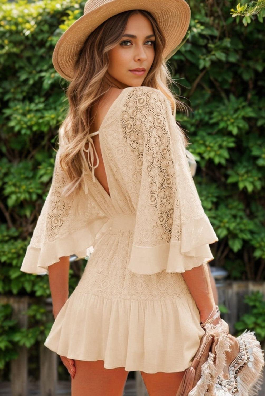 Fashionable woman posing in a cream lace-back mini dress with ruffle details