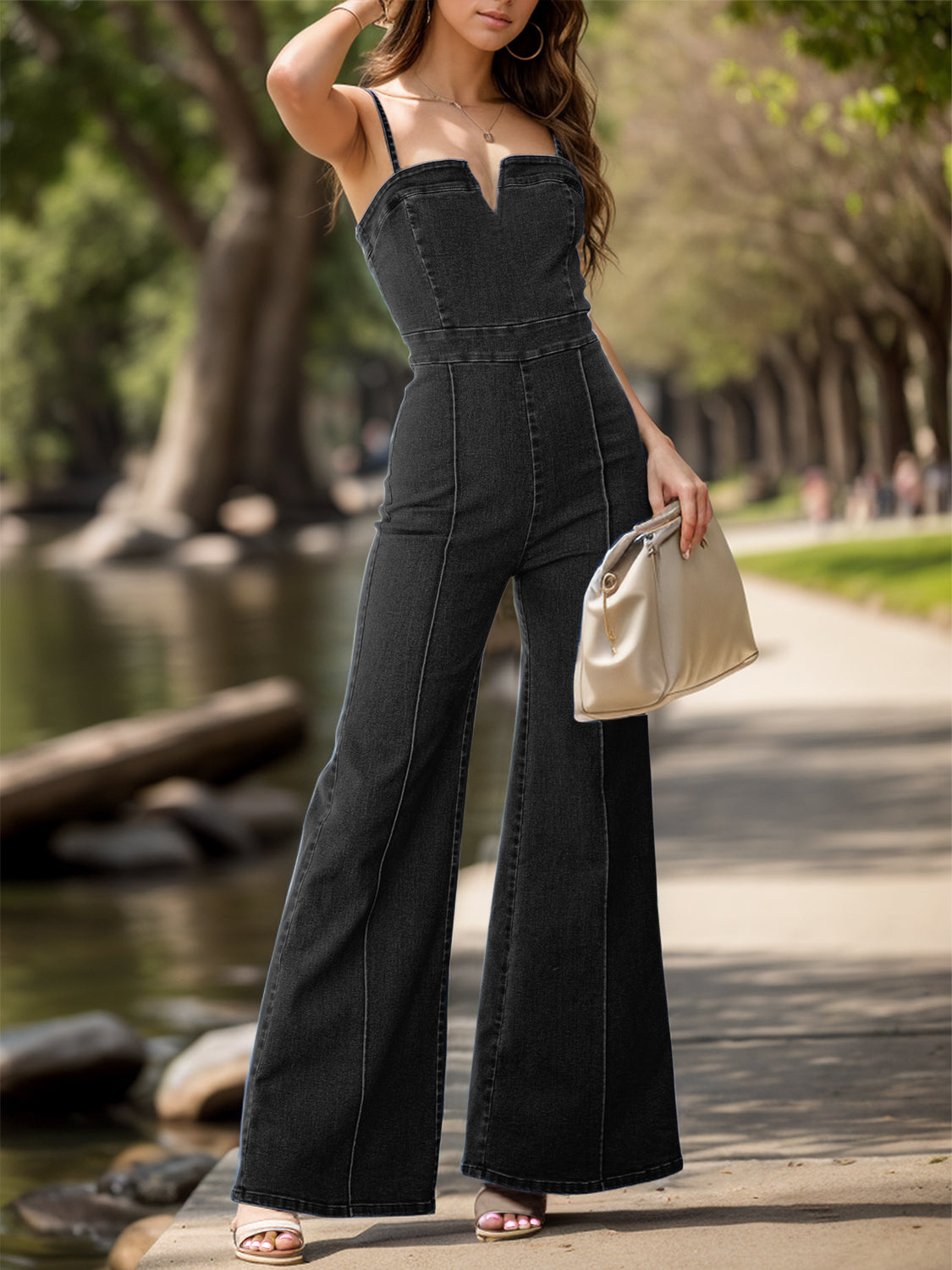 Two images of a woman wearing chic flared denim overalls: one in black and one in blue. Each paired with a white top, she is walking along a tree-lined path, accessorized with a necklace and carrying a cream handbag.