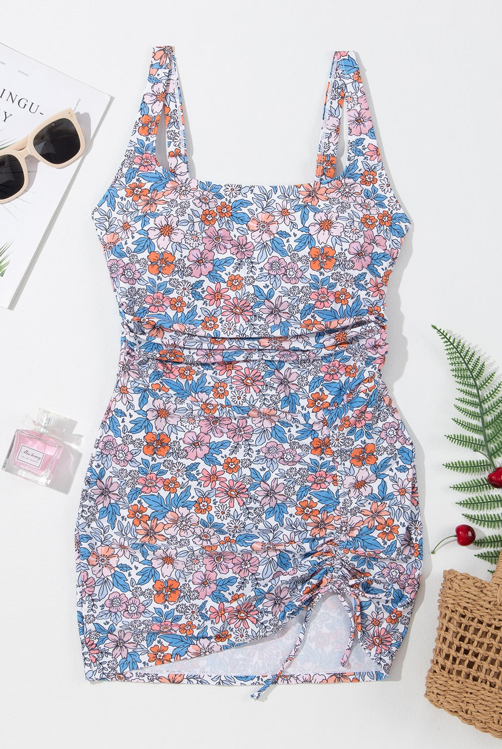 Woman by the sea wearing a stylish floral swim dress with a playful drawstring detail, ready for summer fun.