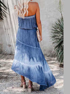 Trendsetting woman in a strapless denim hi-low dress with a stunning tie-dye design, carrying a chic clutch.