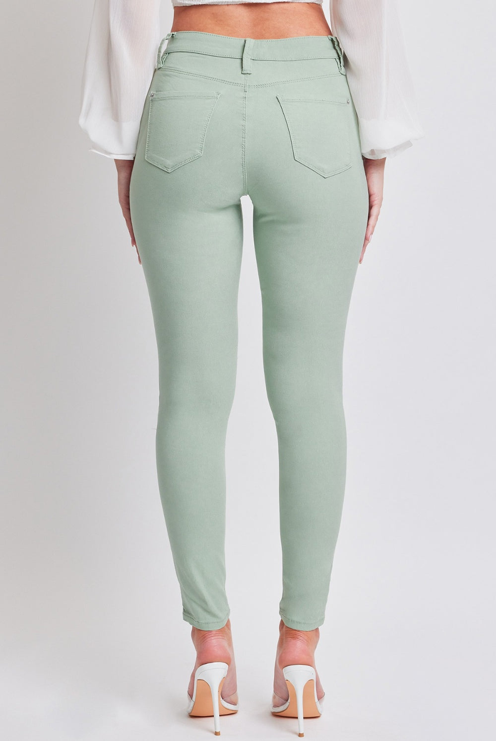 Model wearing stylish jade green mid-rise skinny jeans, exuding confidence and trendy vibes.