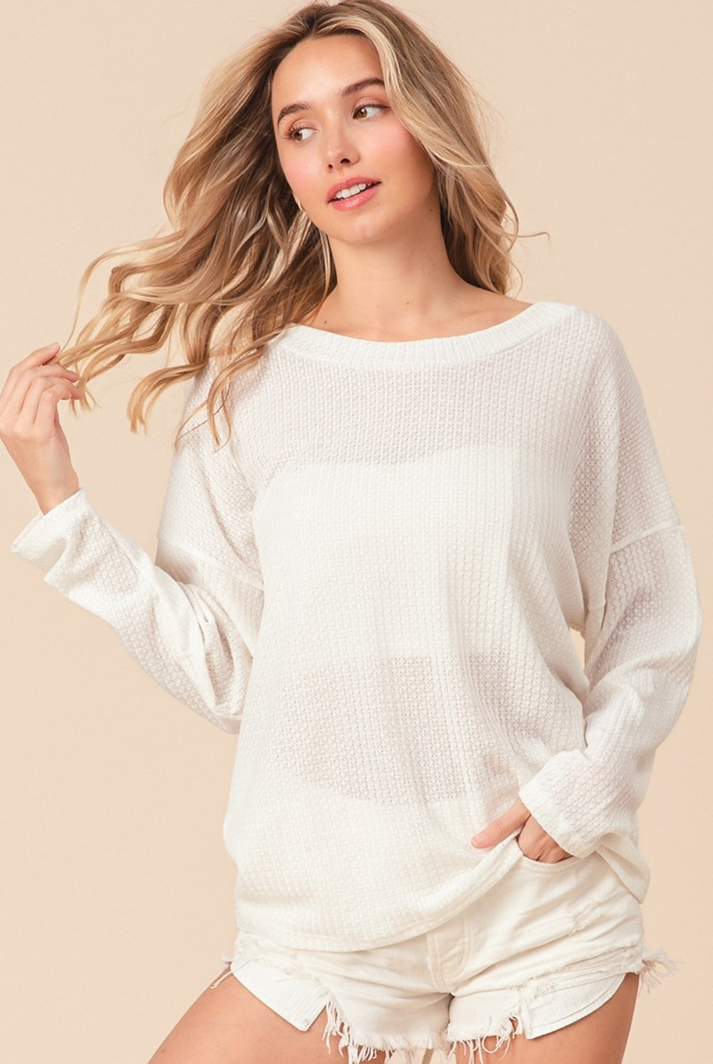A relaxed-fit, waffle-knit top with long sleeves and an adjustable tie-back detail, blending comfort with a hint of allure.