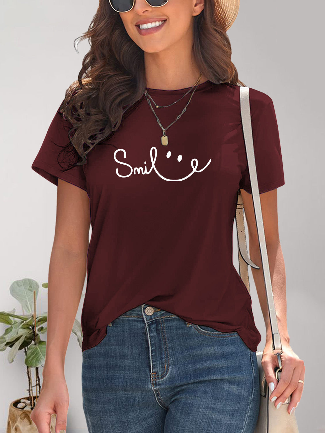 Cheerful woman in a white graphic t-shirt with a 'smile' design, embodying a relaxed and happy vibe.