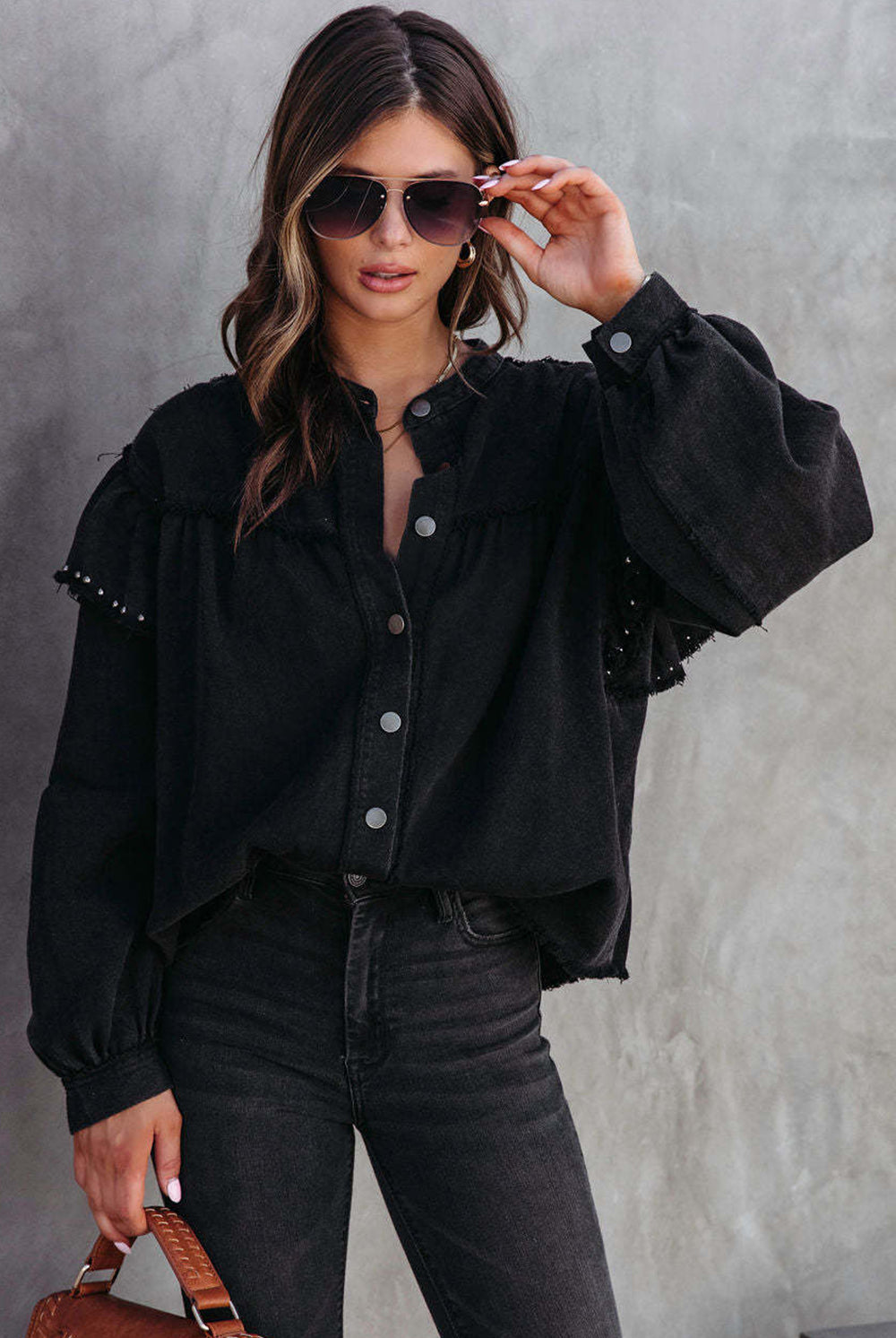A stylish woman sports a black studded button-up jacket with ruffled edges, pairing it effortlessly with dark denim for a look that's both chic and edgy.