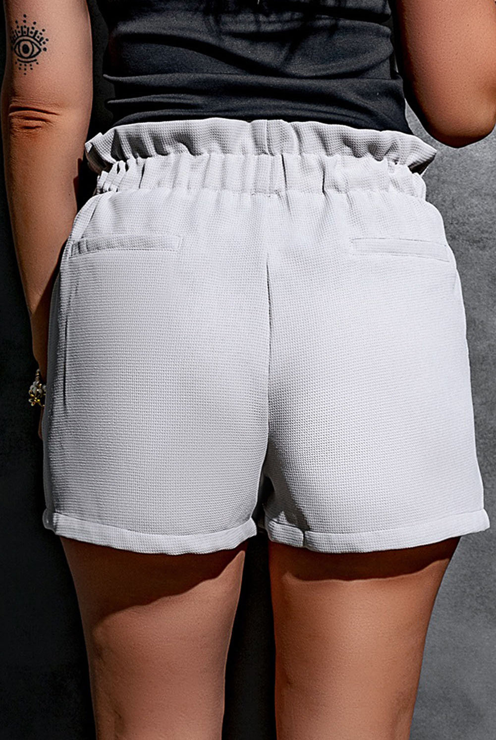 Fashion-forward woman sporting trendy grey paperbag waist shorts with a comfortable fit and button details.