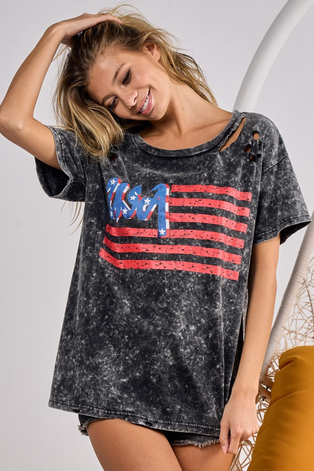 Smiling woman in a trendy American flag-themed t-shirt, embodying a casual and patriotic style.