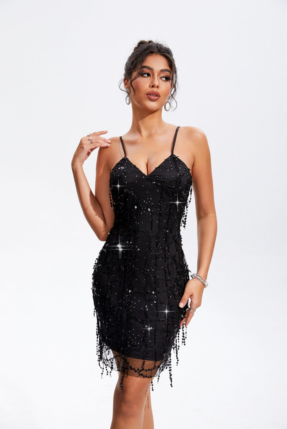 A woman in a black beaded cami dress with fringe detailing, exuding sophistication and poise.