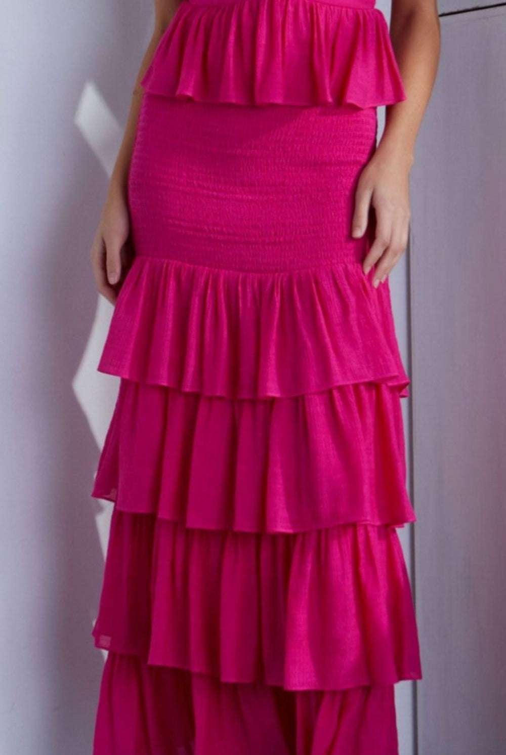 A woman wearing a vibrant pink ruffled dress with layered detailing and a sleeveless design, exuding elegance and playful femininity.