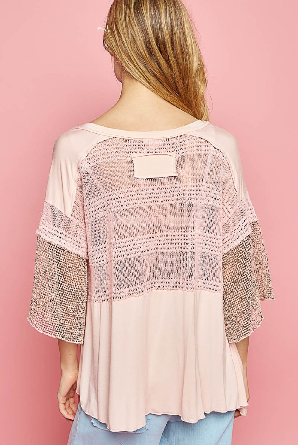 Fashion-forward woman in a blush pink short sleeve knit top with mesh accents