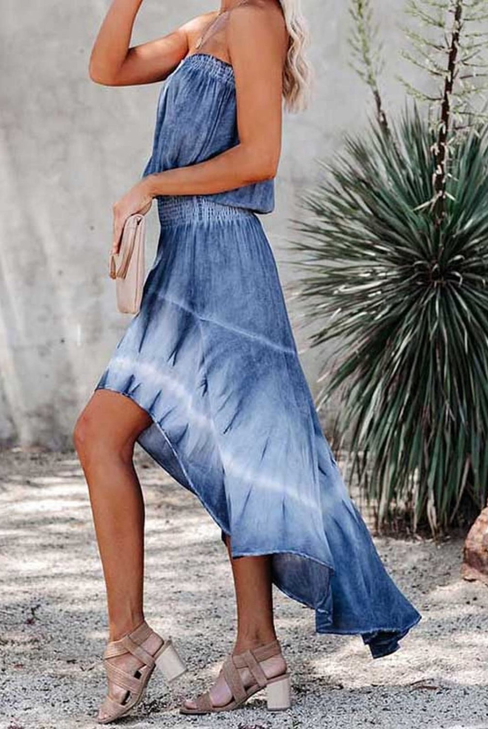 Trendsetting woman in a strapless denim hi-low dress with a stunning tie-dye design, carrying a chic clutch.