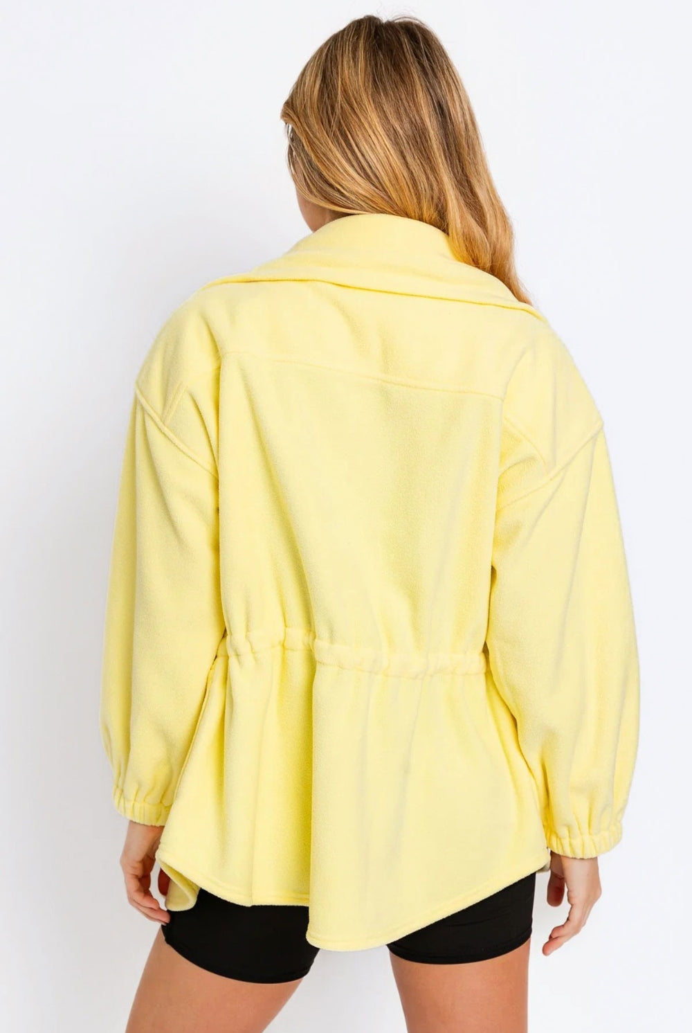 Chic young woman presenting a lemon yellow fleece jacket, ideal for adding a pop of color to a relaxed outfit.