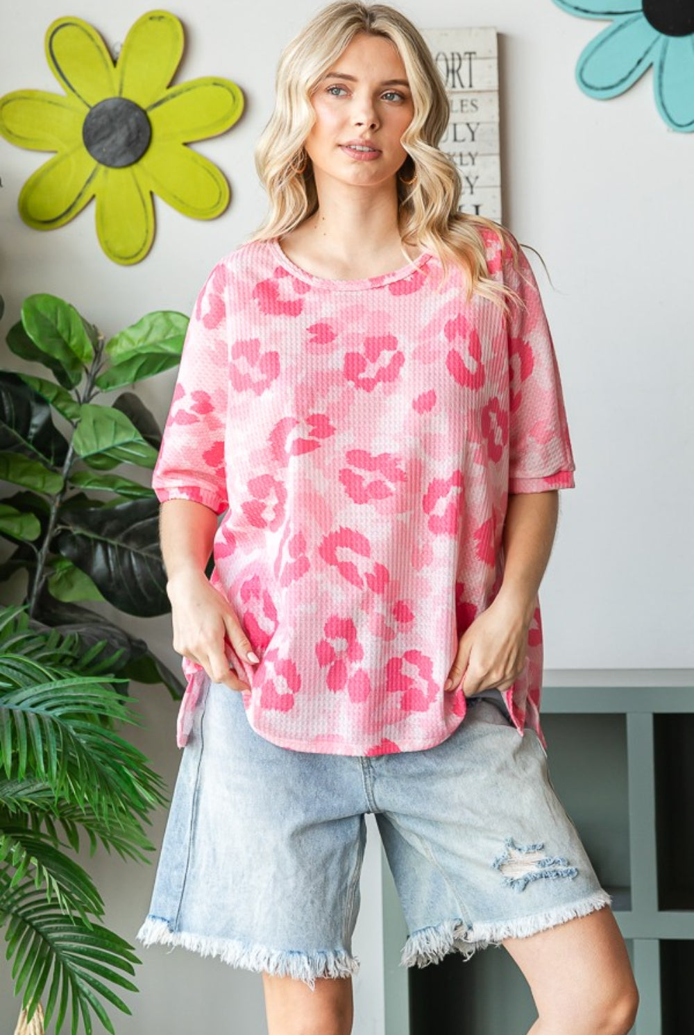 Woman wearing an oversized pink waffle t-shirt with denim shorts, showcasing a relaxed and stylish summer look.