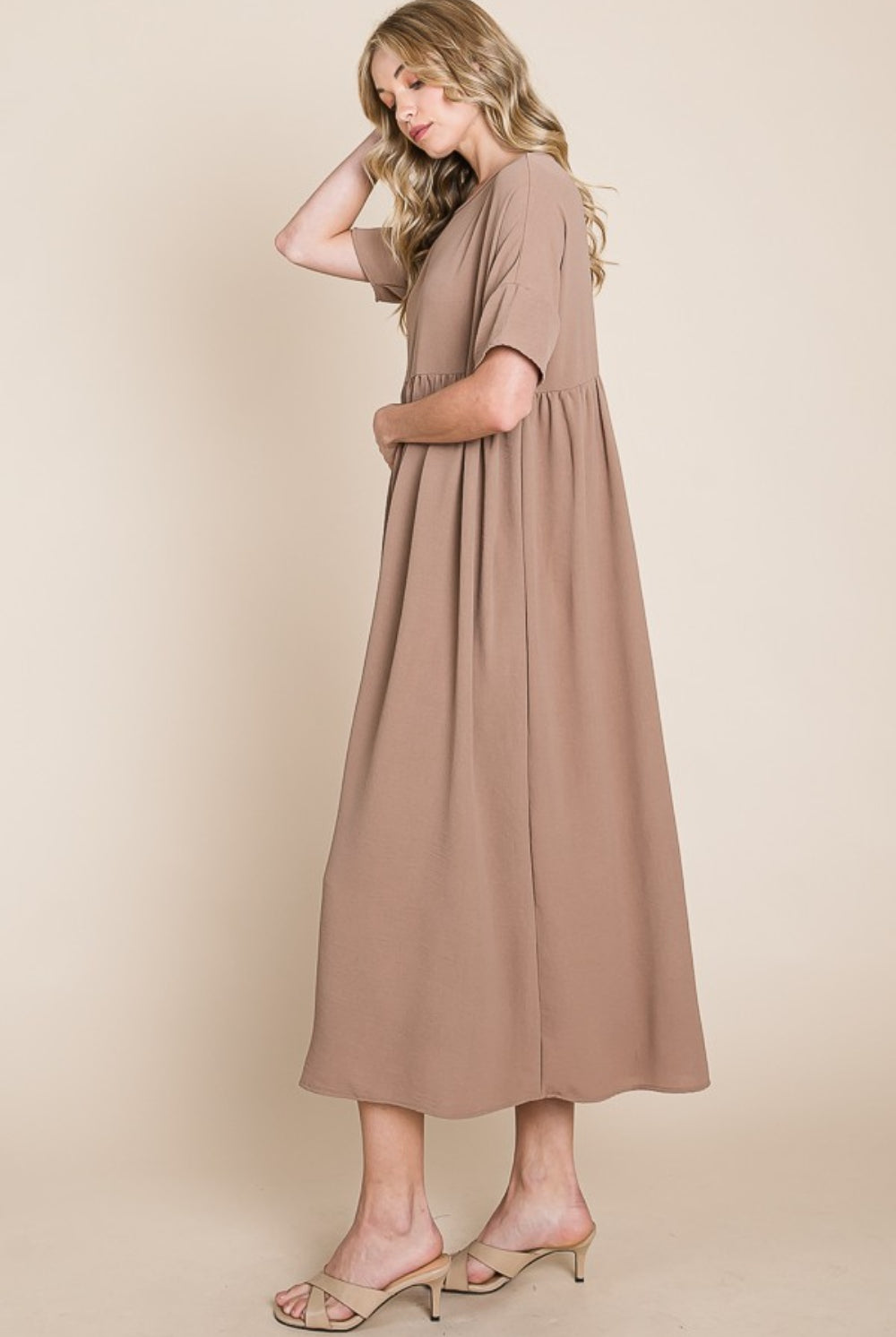 Model wears an Elegant Ruched Midi Dress in a neutral taupe, featuring a flattering waist and flowing skirt, exemplifying classic grace and style.