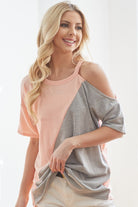 A smiling woman models a modern, asymmetrical one-shoulder t-shirt, blending two contrasting shades for a bold, casual look.