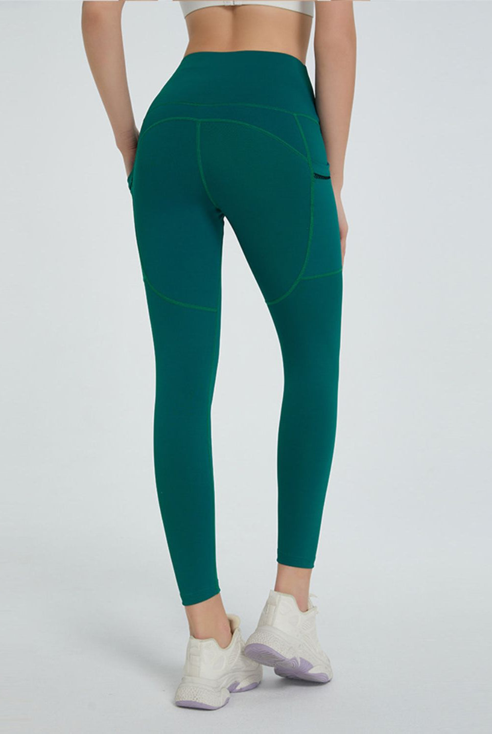 Active woman posing in versatile high-waisted leggings with a handy pocket, paired with athletic sneakers.