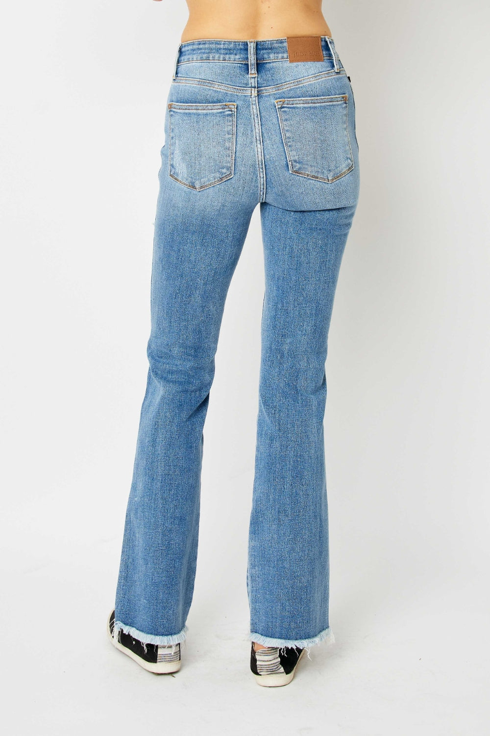 Model wearing light wash women's ripped bootcut jeans with distressed details