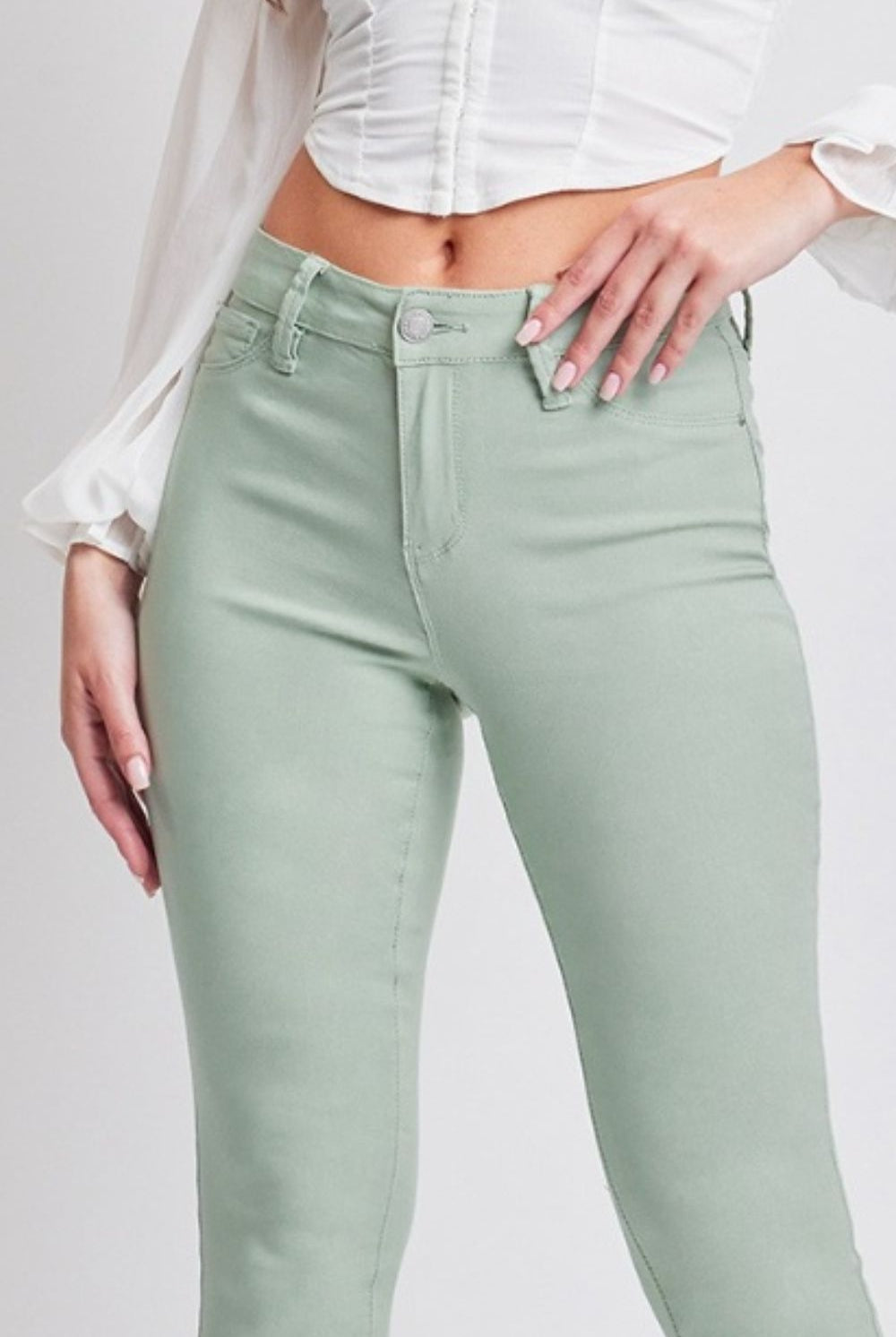 Model wearing stylish jade green mid-rise skinny jeans, exuding confidence and trendy vibes.