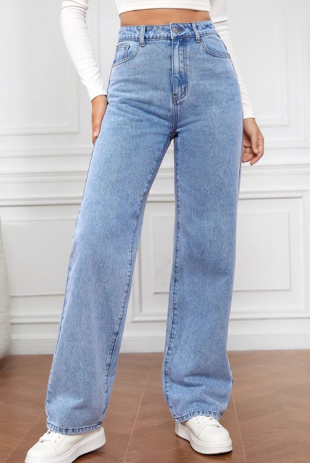 A woman sports the Classic High Waist Straight Jeans in a timeless blue wash, paired with a white crop top and sneakers, embodying a chic yet casual aesthetic.