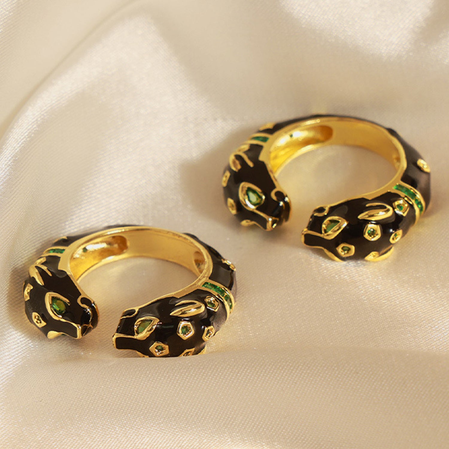 A close-up of a hand with a golden zircon ring shaped like a stylized panther head, featuring black detailing and small gemstone accents that add a touch of luxury and boldness to the jewelry piece. The ring is worn on the middle finger, complementing an elegant and sophisticated style.