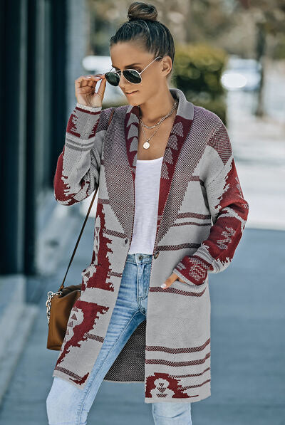 Woman modeling a longline knit cardigan with geometric patterns in maroon, black, and grey, styled with sunglasses and distressed jeans.