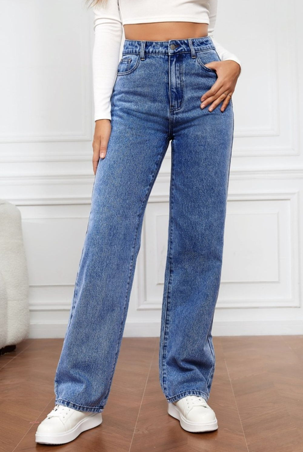 A woman sports the Classic High Waist Straight Jeans in a timeless blue wash, paired with a white crop top and sneakers, embodying a chic yet casual aesthetic.