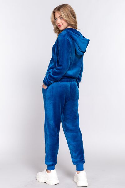 A model wearing a royal blue velvet hoodie and matching joggers set, paired with white sneakers for a relaxed yet stylish look.