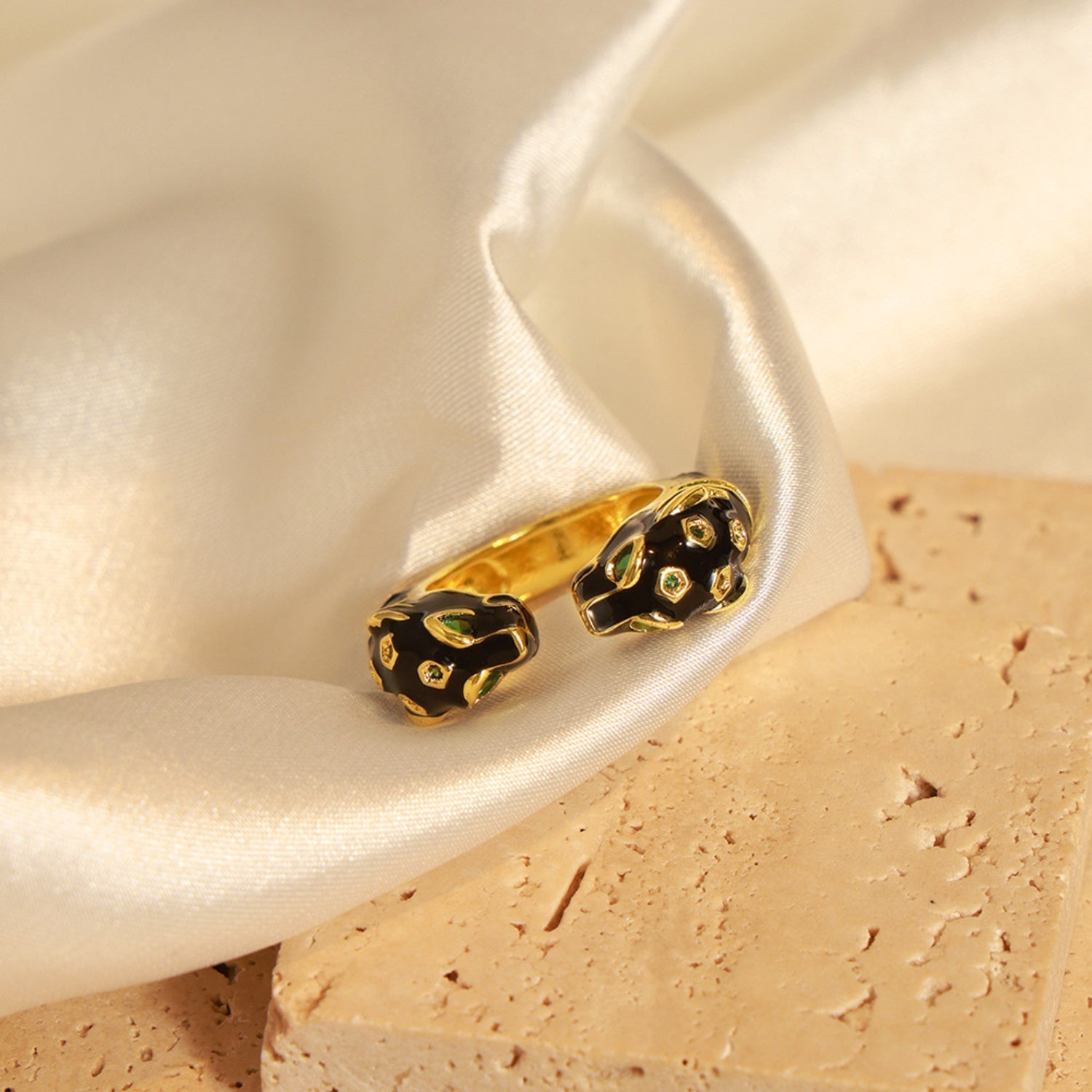 A close-up of a hand with a golden zircon ring shaped like a stylized panther head, featuring black detailing and small gemstone accents that add a touch of luxury and boldness to the jewelry piece. The ring is worn on the middle finger, complementing an elegant and sophisticated style.