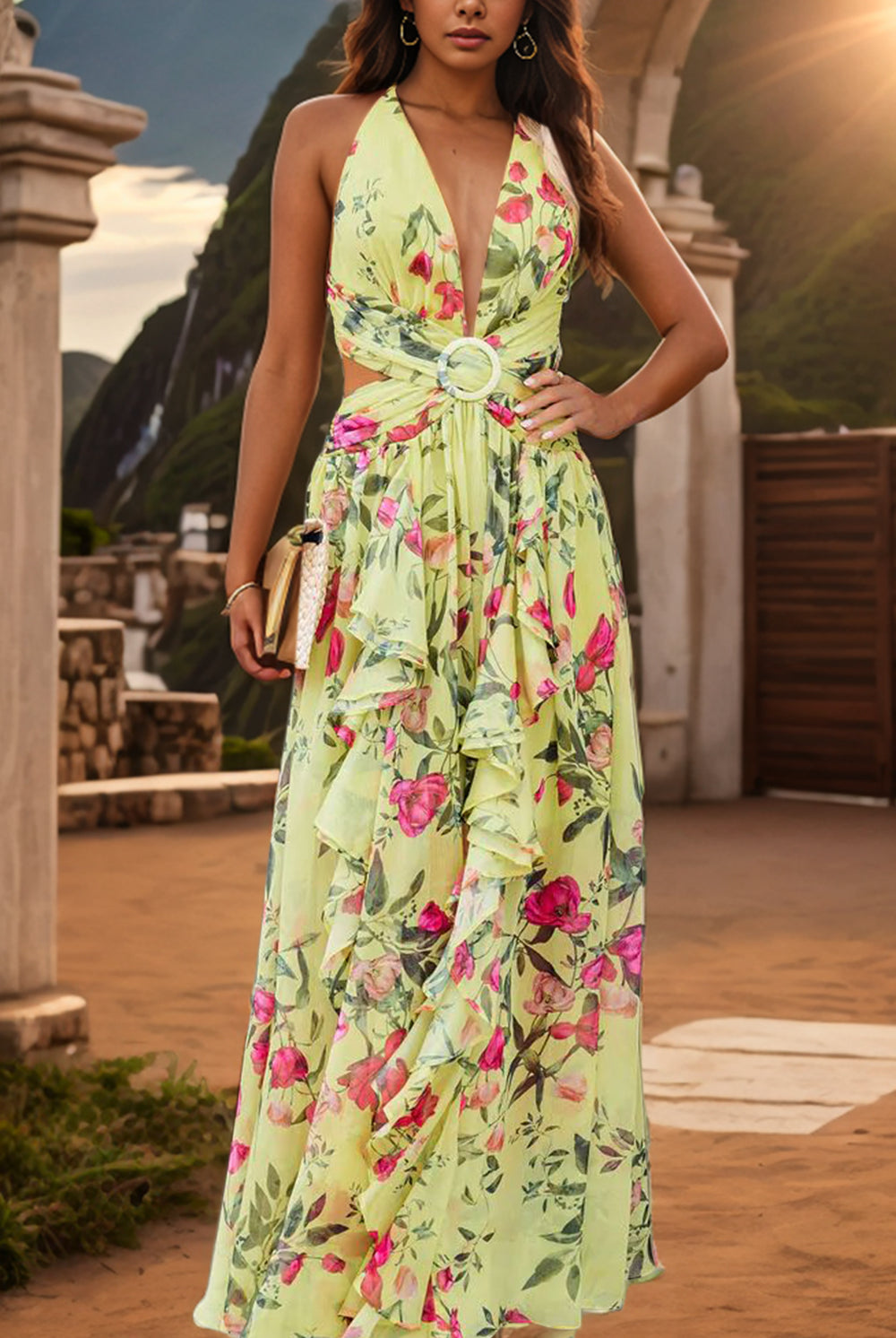 A woman stands poised against a sunset backdrop, wearing an elegant sleeveless maxi dress adorned with a vibrant floral pattern in shades of pink and green. The dress features a plunging neckline, cinched waist with a decorative ring detail, and a flowing ruffled skirt, embodying a graceful summer evening aesthetic.