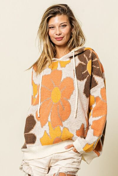 A woman wearing an oversized knit hoodie sweater with a bold floral pattern, casual for a relaxed and stylish look.