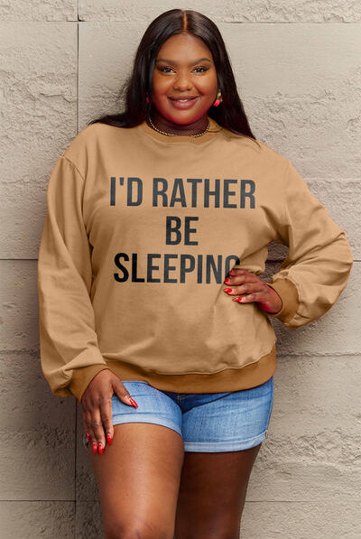 Woman modeling a brown round neck sweatshirt with the text "I'D RATHER BE SLEEPING" printed on the front, paired with white shorts.