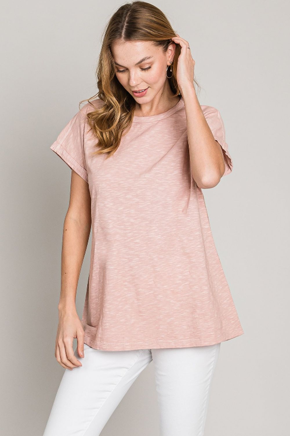 A woman in a casual, mauve cotton t-shirt, paired with white pants for a relaxed and stylish everyday look.