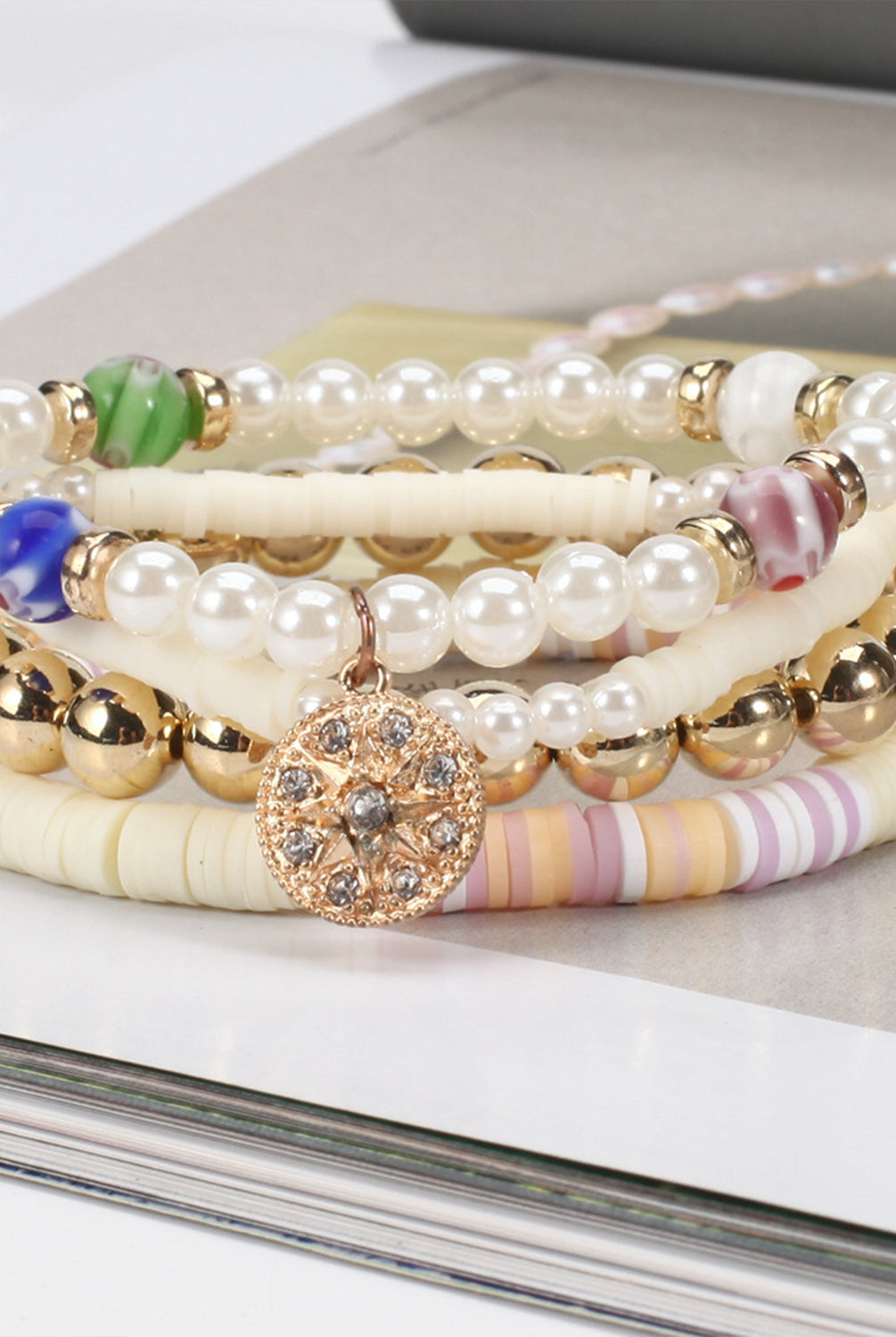 Elegant soft pottery bead bracelet with pearls, gold spheres, and a central sparkling charm.