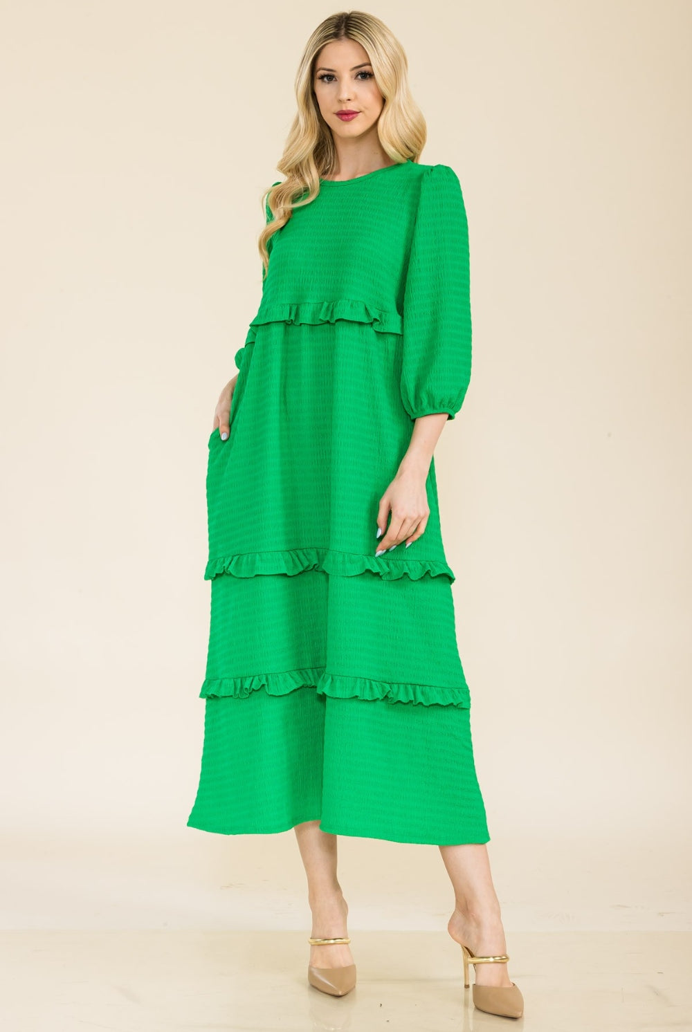 Woman wearing a green tiered ruffle midi dress with long sleeves.