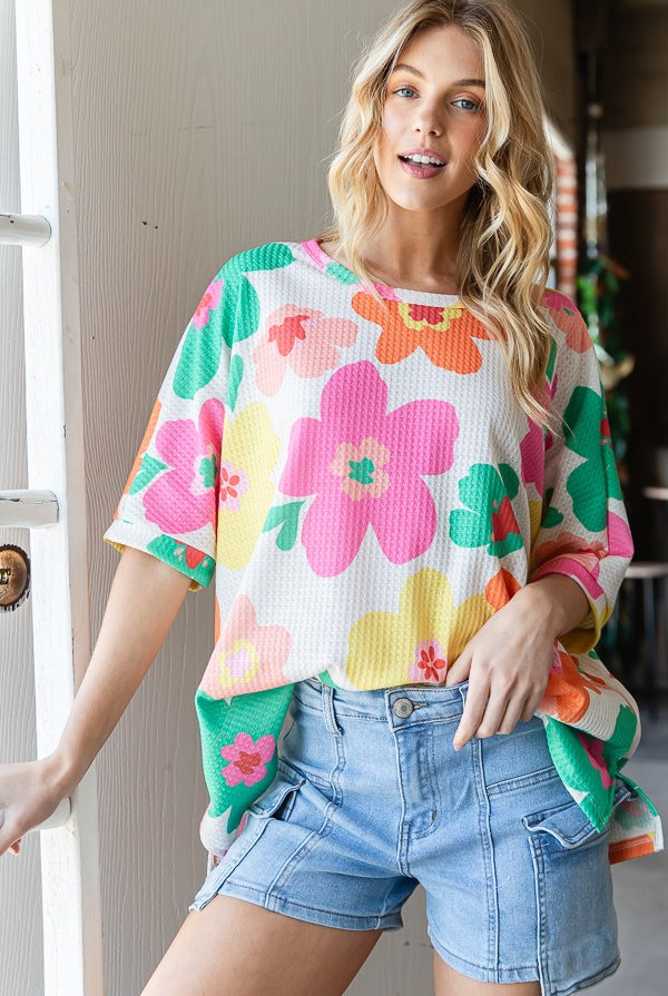 Woman wearing an oversized floral waffle T-shirt in off white, perfect for a casual and vibrant look.