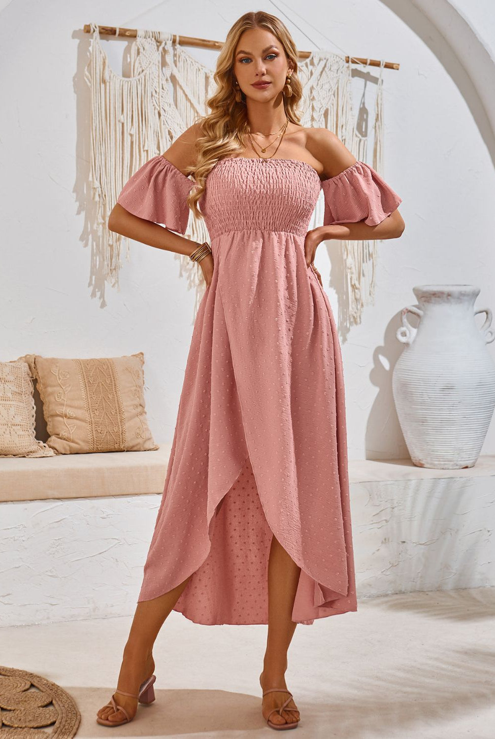 Woman in a chic pale blush smocked midi dress with a high-low hem, perfect for a summer day.