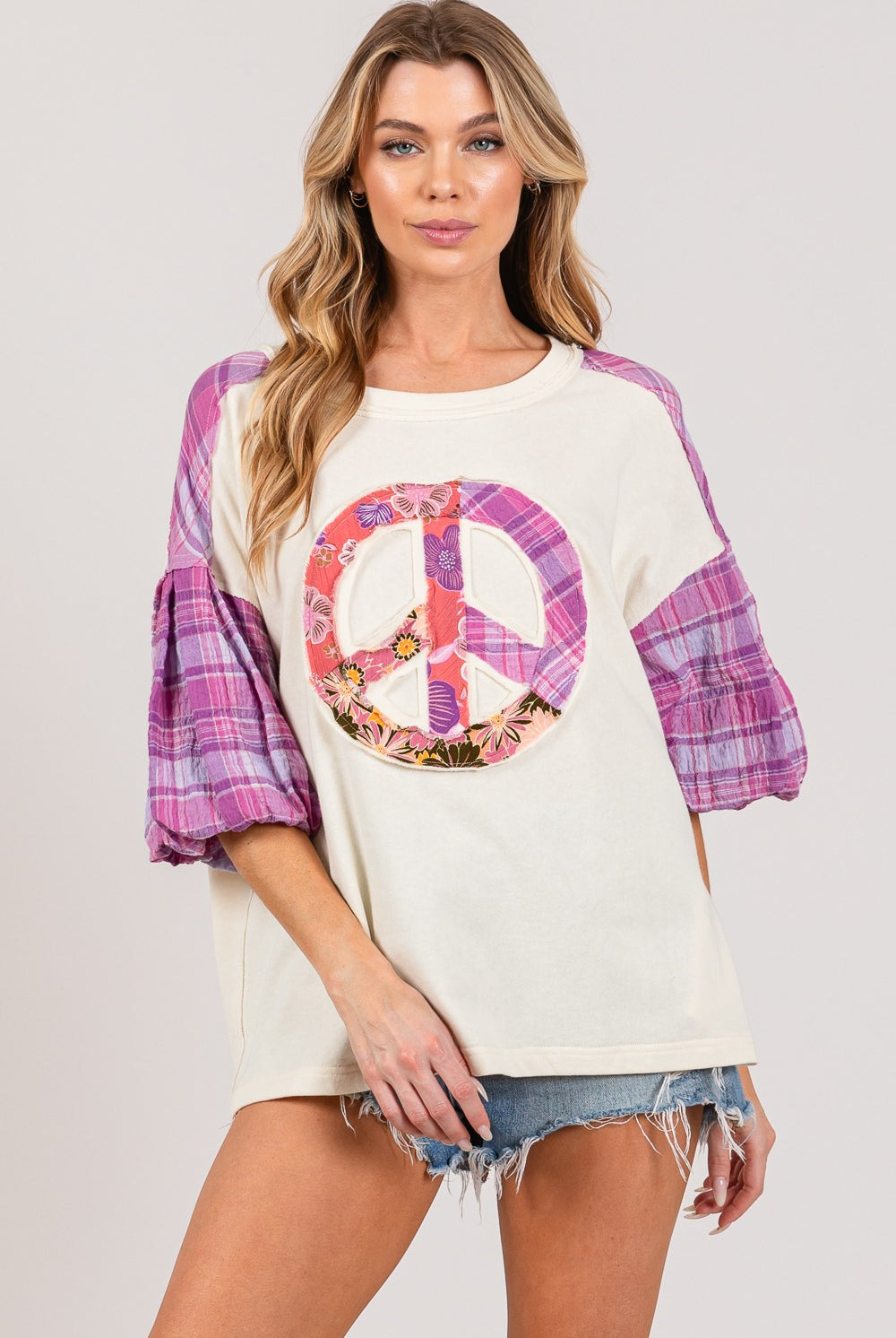 Woman in a casual peace sign top with plaid sleeves, perfect for a stylish contrast look.