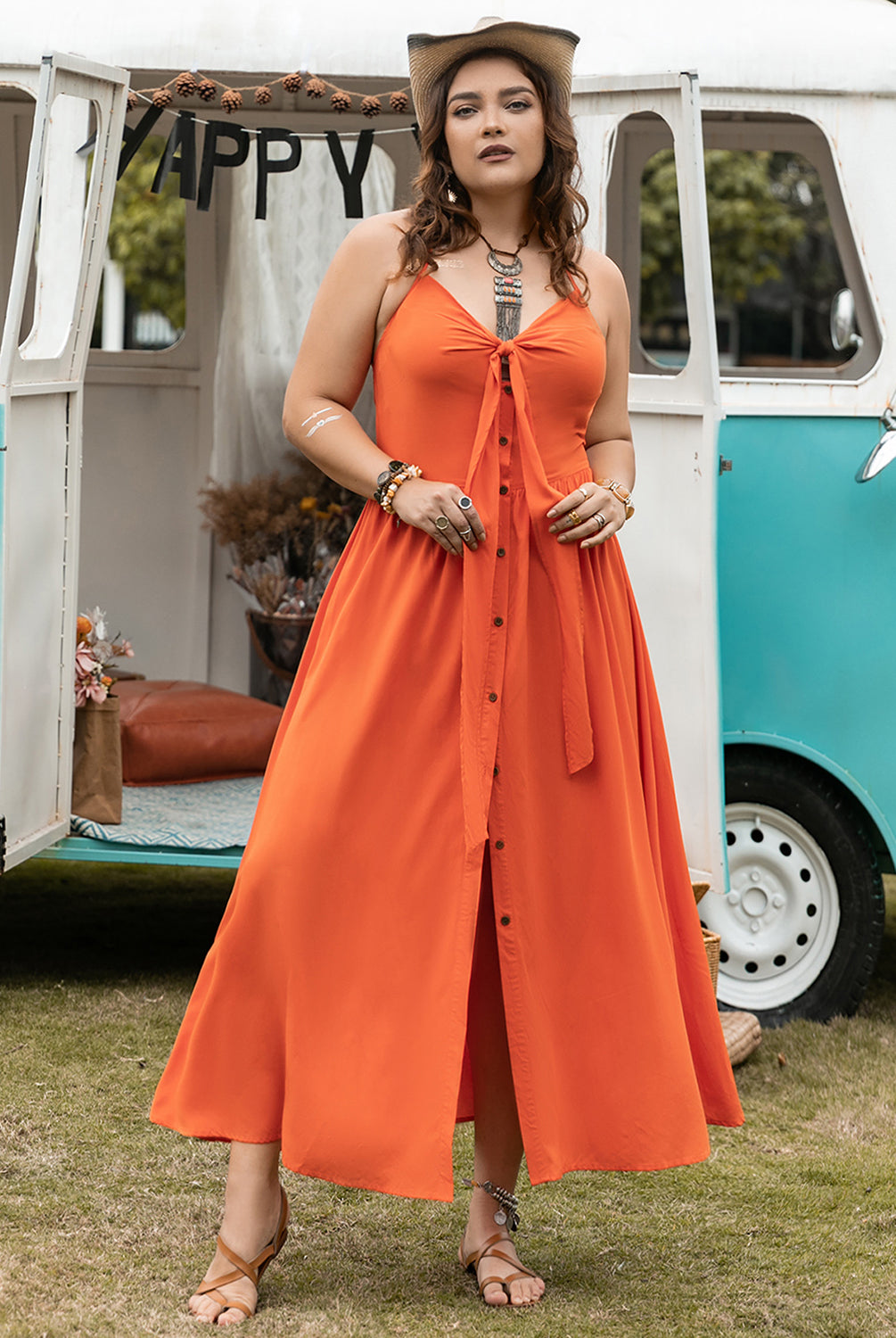 Woman wearing a vibrant orange plus size halter neck midi dress, standing in front of a decorated camper van.