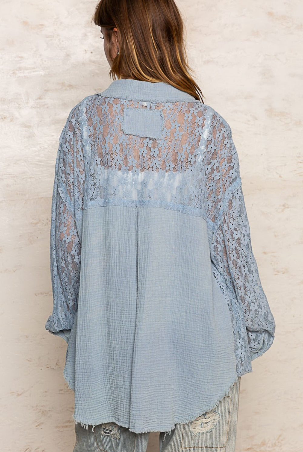 A woman in a delicate light blue lace button-down shirt, combining classic elegance with modern lace detailing for a sophisticated look.
