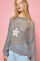 Cheerful woman posing in a grey knit long sleeve top with star detail