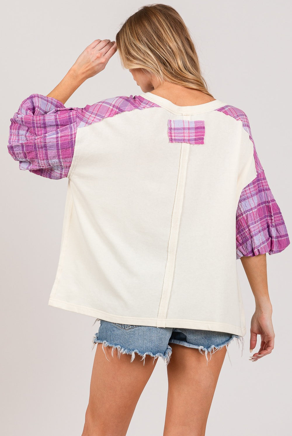 Woman in a casual peace sign top with plaid sleeves, perfect for a stylish contrast look.