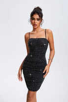 A woman in a black sequined cami dress with thin straps and a straight neckline, exuding elegance and ready for an evening event.