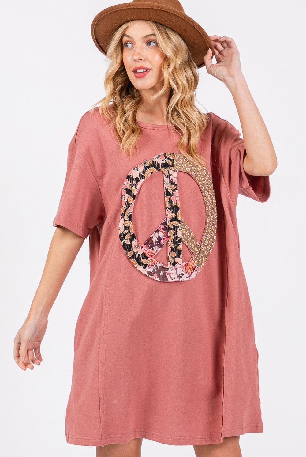 Woman wearing a casual short sleeve tee dress with a peace sign applique.